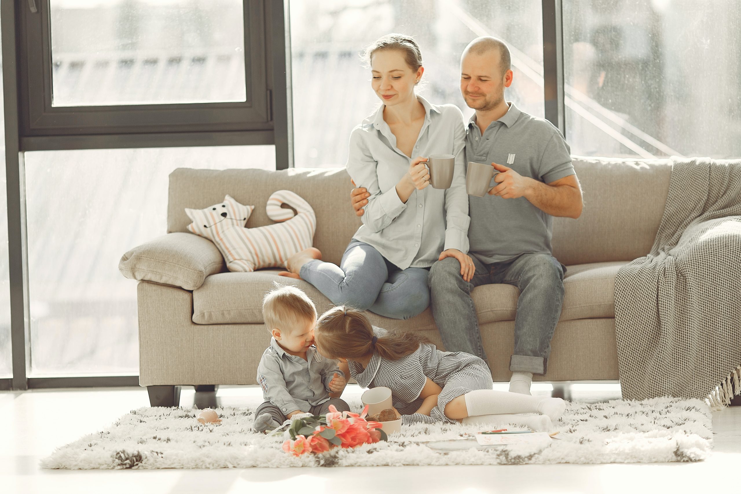 Funny Family Portrait. Happy Parents And Children Posing Lying On Floor Together Looking At Camera At Home. Free Space